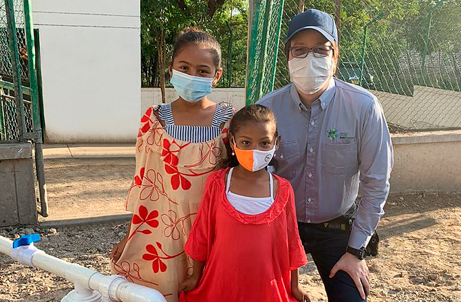 Operario de TGI y dos niñas de la comunidad wayú sonríen