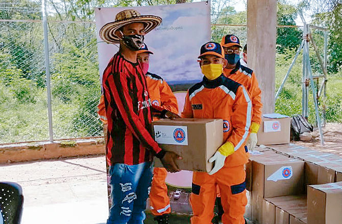 Personal de la Defensa Civil entrega cajas con ayudas humanitarias a un joven de la comunidad