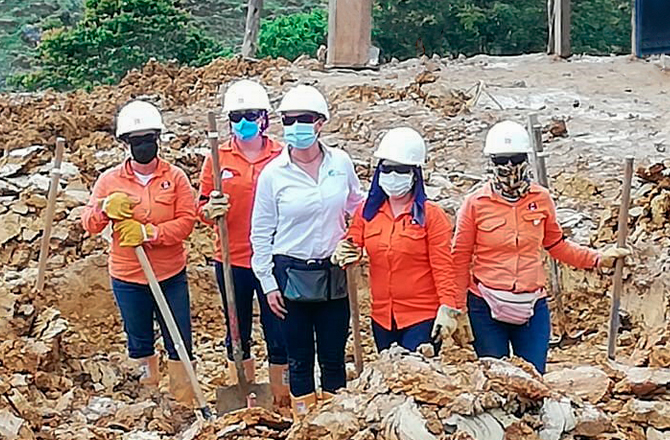 Cinco mujeres en trabajo de campo llevan pala en mano