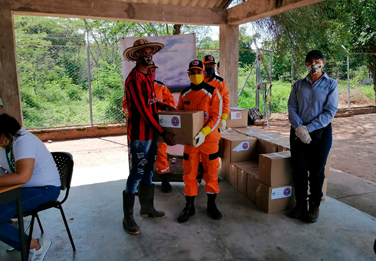Personal de la Defensa Civil entrega cajas con ayudas humanitarias a un joven de la comunidad