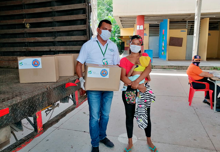 Una familia con bebé reciben una caja con ayudas humanitarias