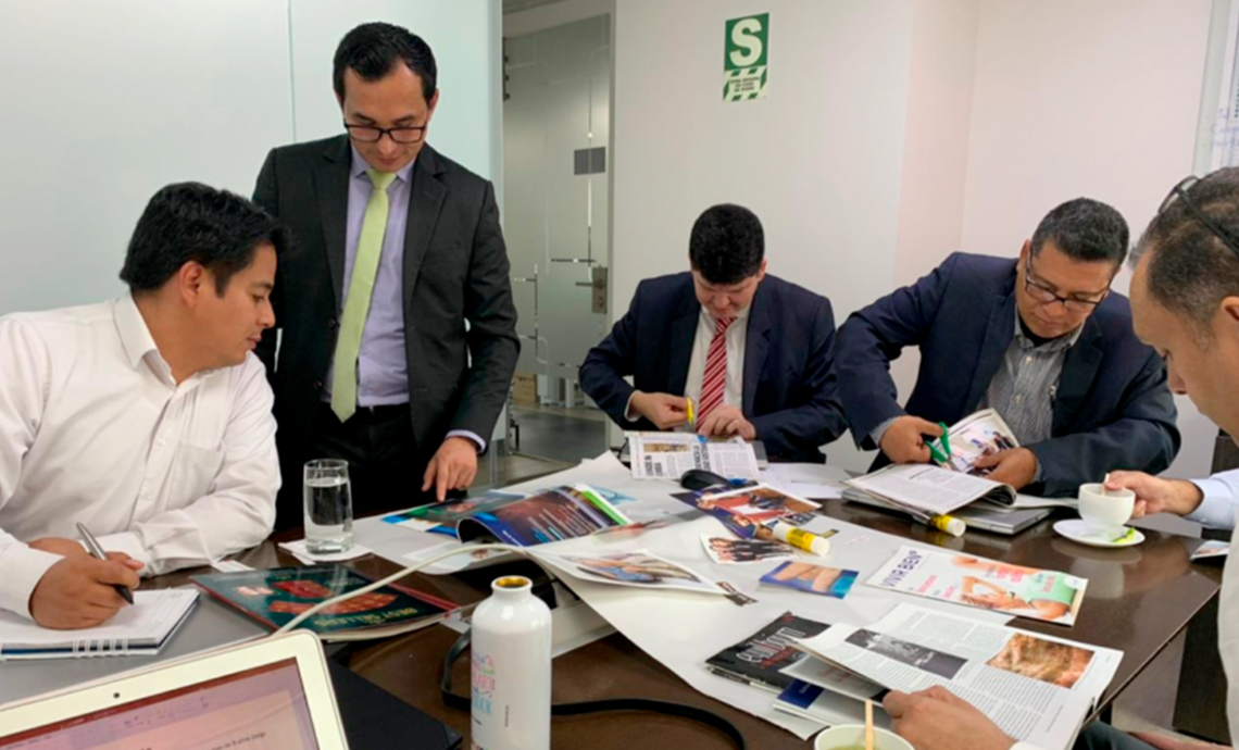 Cinco ejecutivos reunidos en una mesa revisando papeles