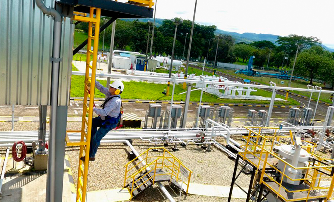 Un operario subiendo una escalera de hierro amarillo a las afueras de la infraestructura