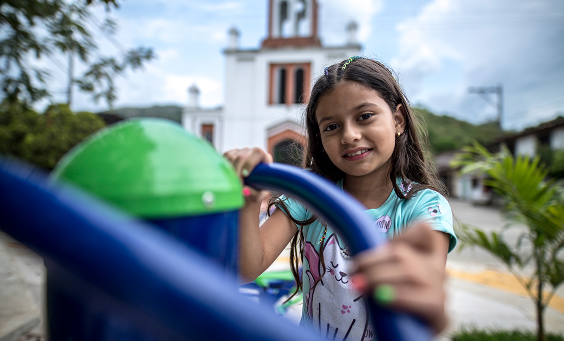 Una niña juega en el parque principal y está de espaldas a la iglesia