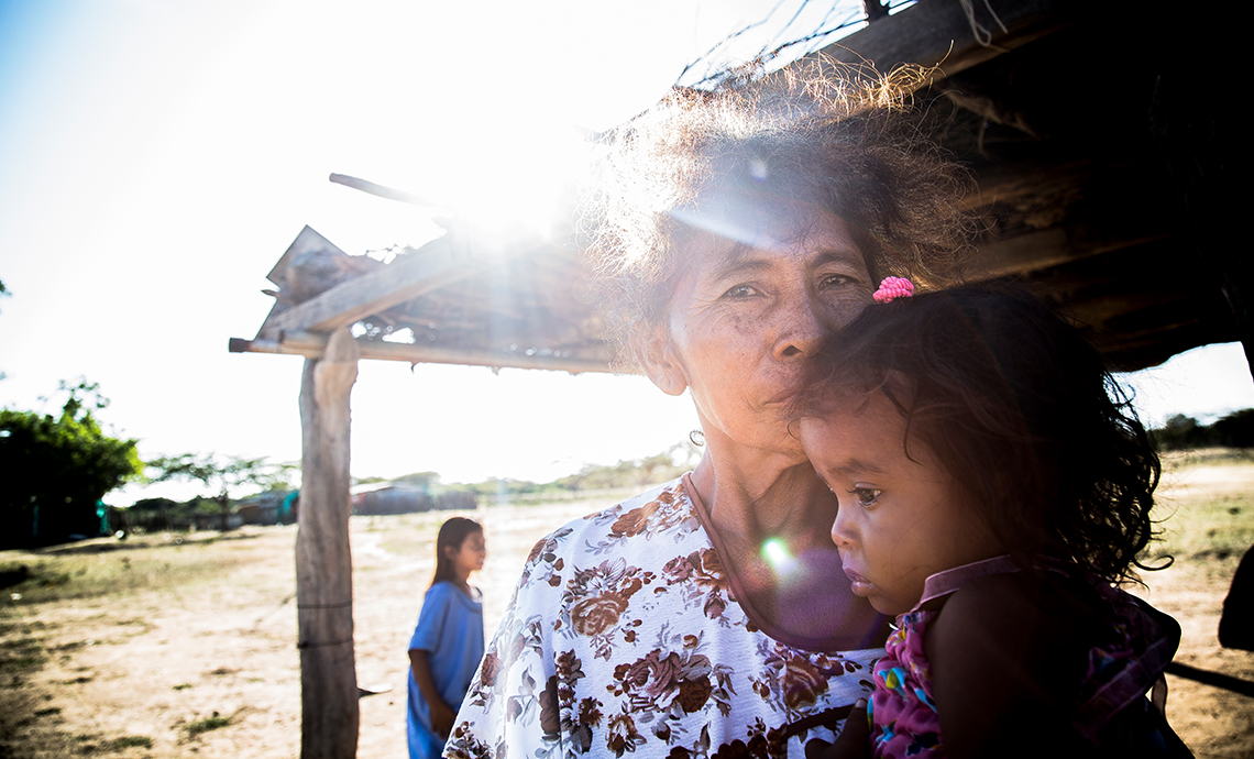 Abuela de la comunidad wayú carga a su nieta pequeña en brazos